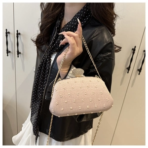Detail of light pink evening clutch featuring a luxury rhinestone buckle and gold chain