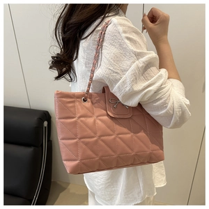 Detail of pink quilted tote bag featuring a silver bow buckle and chain shoulder strap