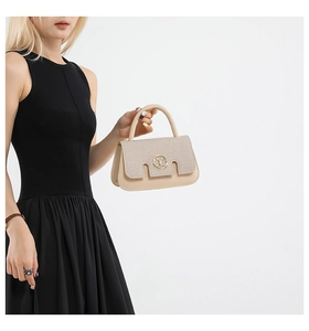 Detail of beige flap bag featuring woven texture and golden circular letter M logo