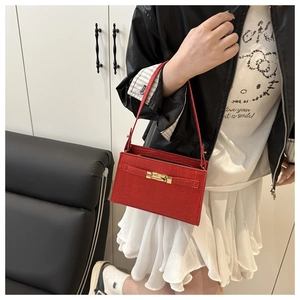 Detail of red crocodile texture handbag with golden twist lock worn by a model