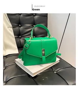 Detalle de bolso de mano verde minimalista con cierre giratorio de metal en libro