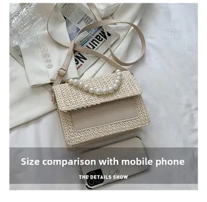 Detail show of woven crossbody bag with pearl handle compared to a smartphone for size scale