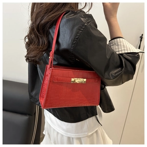 Detail of red crocodile texture PU leather shoulder bag with gold turn-lock closure