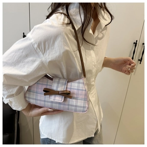 Detailed view of a pink plaid baguette bag with a brown bow and slim shoulder strap