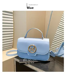 Detail of light blue handbag featuring a gold M letter buckle on black prop books