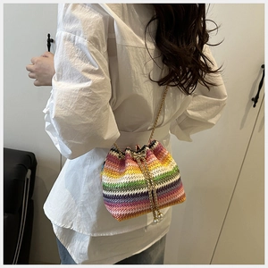 Détail d'un sac seau tissé coloré avec chaîne dorée et élégants cordons en perles