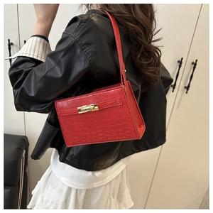 Detail of red crocodile pattern PU handbag featuring a golden twist lock closure