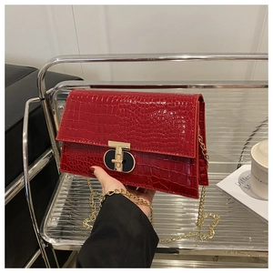 Close-up of red crocodile pattern handbag with golden T-shaped metal clasp and chain