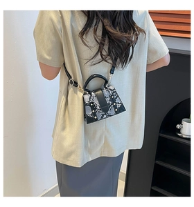 Chic snakeskin textured crossbody bag with gold studs shown on a model's shoulder