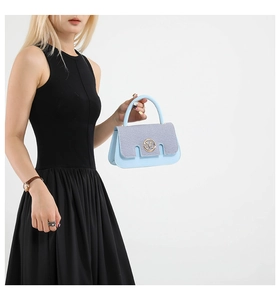 Detail of light blue and grey paneled crossbody bag with golden M metal hardware