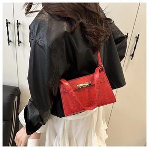 Detail of red crocodile texture mini bag with gold twist lock on black and white outfit