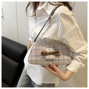 Close-up of checkered bag with leather bow detail and slim shoulder strap