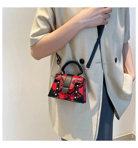 Detailed view of red snake print mini bag with gold studs on beige blazer outfit