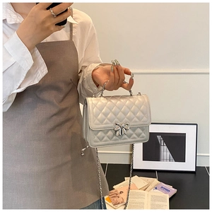 Close-up of champagne silver quilted crossbody bag with a metal bow twist-lock buckle