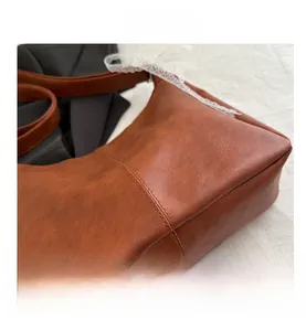 Close-up of brown faux leather tote bag showing detailed hand-stitched bottom and retro texture