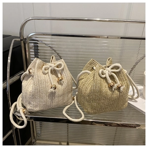 Close-up of straw bucket bag texture with drawstring closure and metallic bead details