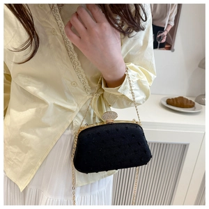 Detail of luxury black evening bag with gold frame, rhinestone clasp and chain strap