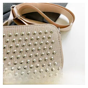 Detail of champagne gold woven fabric with conical metal studs and wide crossbody strap