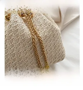 Detail of straw bucket bag featuring beige woven texture, gold chain and pearl accents