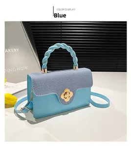 Detail of blue textured fabric bag with floral gold lock and braided handle on a table