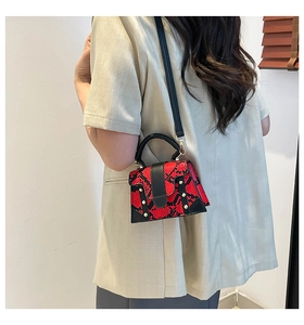 Fashionable snake print handbag with gold studs worn by model on a side-shoulder view