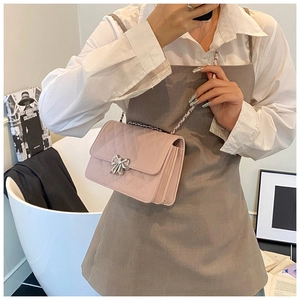 Détail du sac à chaîne rose matelassé avec un fermoir décoratif en métal à nœud argenté
