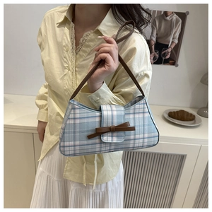 Detail of plaid baguette bag with bow accent and brown leather strap on model