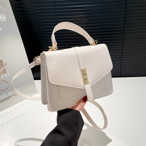 Bolso blanco minimalista con herrajes dorados y asa superior mostrado en la mano