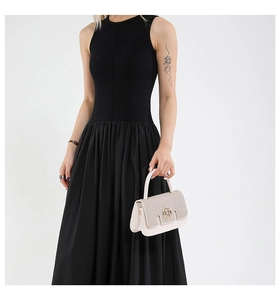 Detail of cream flap handbag with gold metal clasp carried by model in black dress