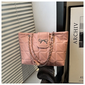 Close-up of pink quilted tote bag with silver bow clasp and metal chain strap