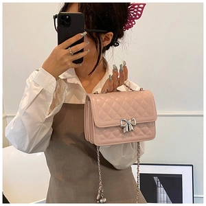 Détail du sac à bandoulière matelassé rose avec nœud argenté et chaîne métallique