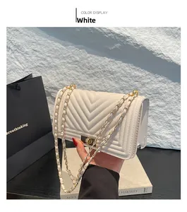 Detail of cream quilted crossbody bag featuring V-shaped stitching and gold chain strap