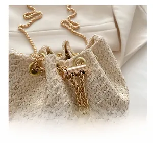 Detailed close-up of shiny gold metal hardware and chain strap on straw bucket bag