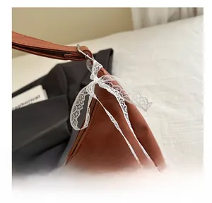 Detail of caramel PU leather bag with white lace bow and smooth zipper closure
