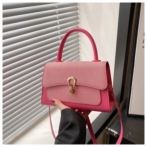 Detail of fuchsia leather bag featuring textured woven flap and gold teardrop lock