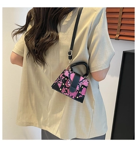 Detail view of pink snakeskin pattern square bag with black handle and gold hardware detail