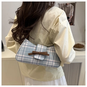 Detail view of plaid underarm bag with leather bow on a model for sweet campus style