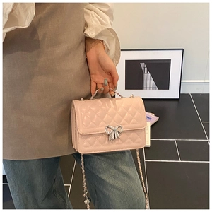 Detailed view of pink quilted handbag featuring a silver bow metal buckle and chain strap