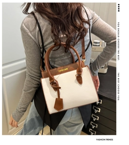 Detail view of contrast leather handbag featuring white body and brown textured flap