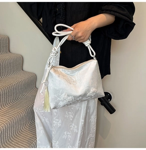 Detail of white lace shoulder bag with butterfly embroidery and braided rope handle