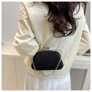 Detail of elegant black evening bag with textured dots, rhinestones and gold chain strap