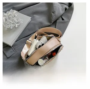 Detail showing the inner capacity of this beige camera bag with a phone and lipstick