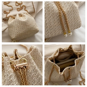 Detail of beige straw bucket bag with gold chain strap, pearls and drawstring closure