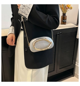 Chic silver mini bag featuring a gold ring handle and chain strap on a black suit
