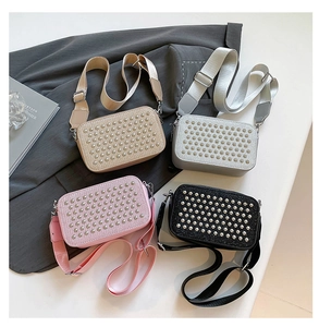 Detail view of four square crossbody bags with silver rivets and wide textile straps