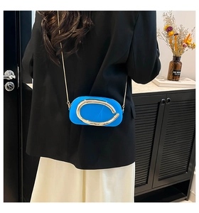 Detail of royal blue mini crossbody bag with gold round metal buckle and chain strap