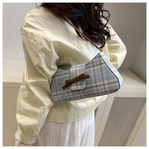 Detail of blue plaid baguette bag with brown leather bow and slim shoulder strap