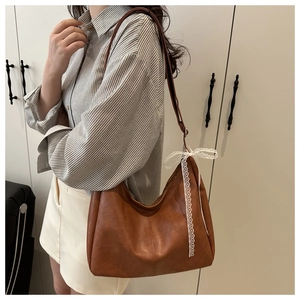 Detail of brown faux leather tote bag with white lace bow on shoulder of model