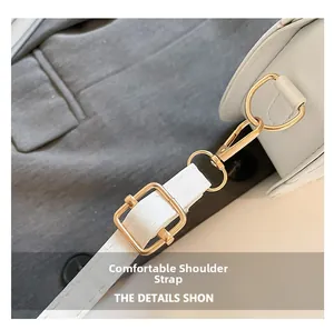 Detail of adjustable white leather strap with gold buckle and lobster clasp on bag