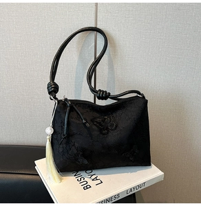 Detail of black jacquard shoulder bag featuring butterfly embroidery and pearl tassel charm